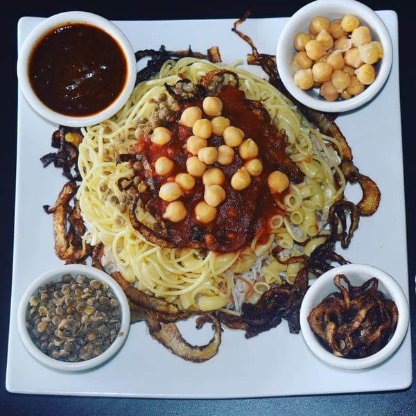 King of Koshary's koshary dish with pasta, rice, lentils, chickpeas, sauce, and fried onions.