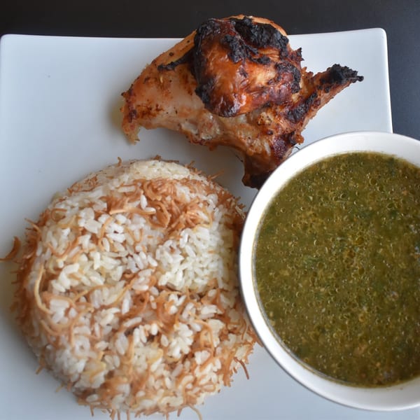 Grilled chicken, rice with vermicelli, and a bowl of green molokhia soup on a white plate.