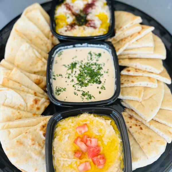 A platter of King of Koshary's hummus and baba ghanoush dips with pita bread.