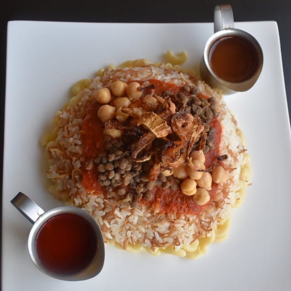 King of Koshary's koshary dish with rice, lentils, chickpeas, fried onions, and tomato sauce.